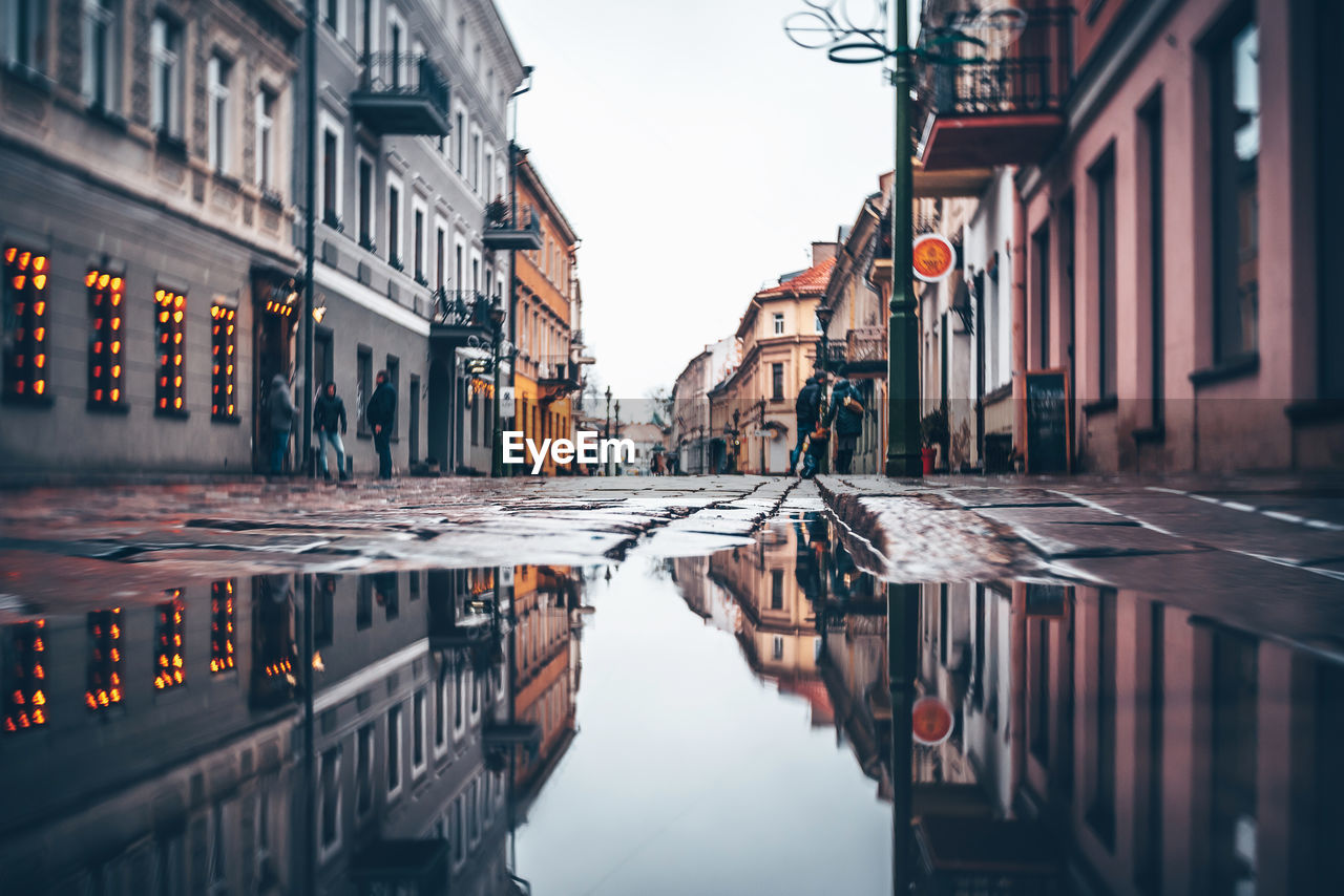 REFLECTION OF BUILDINGS ON PUDDLE IN CITY