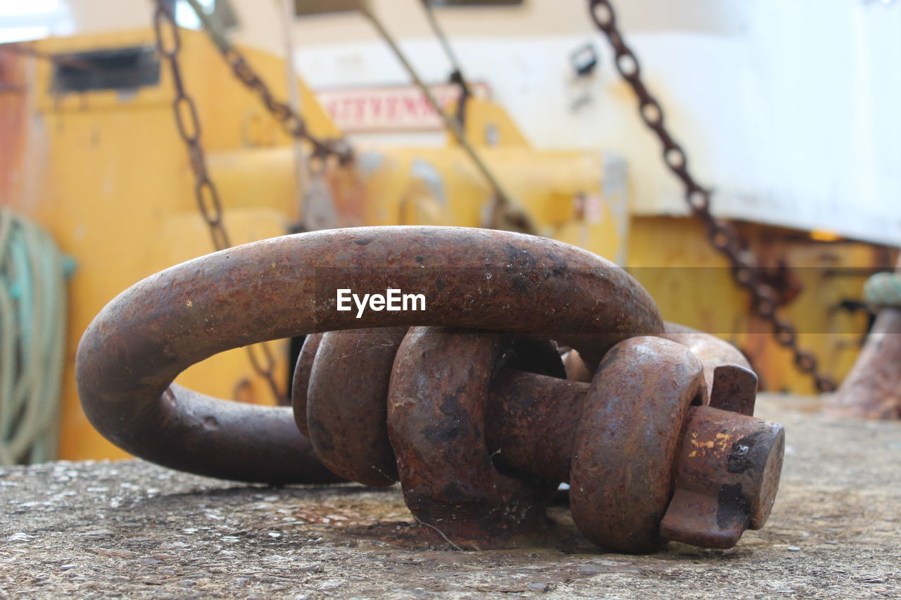CLOSE-UP OF RUSTY CHAIN ON METAL