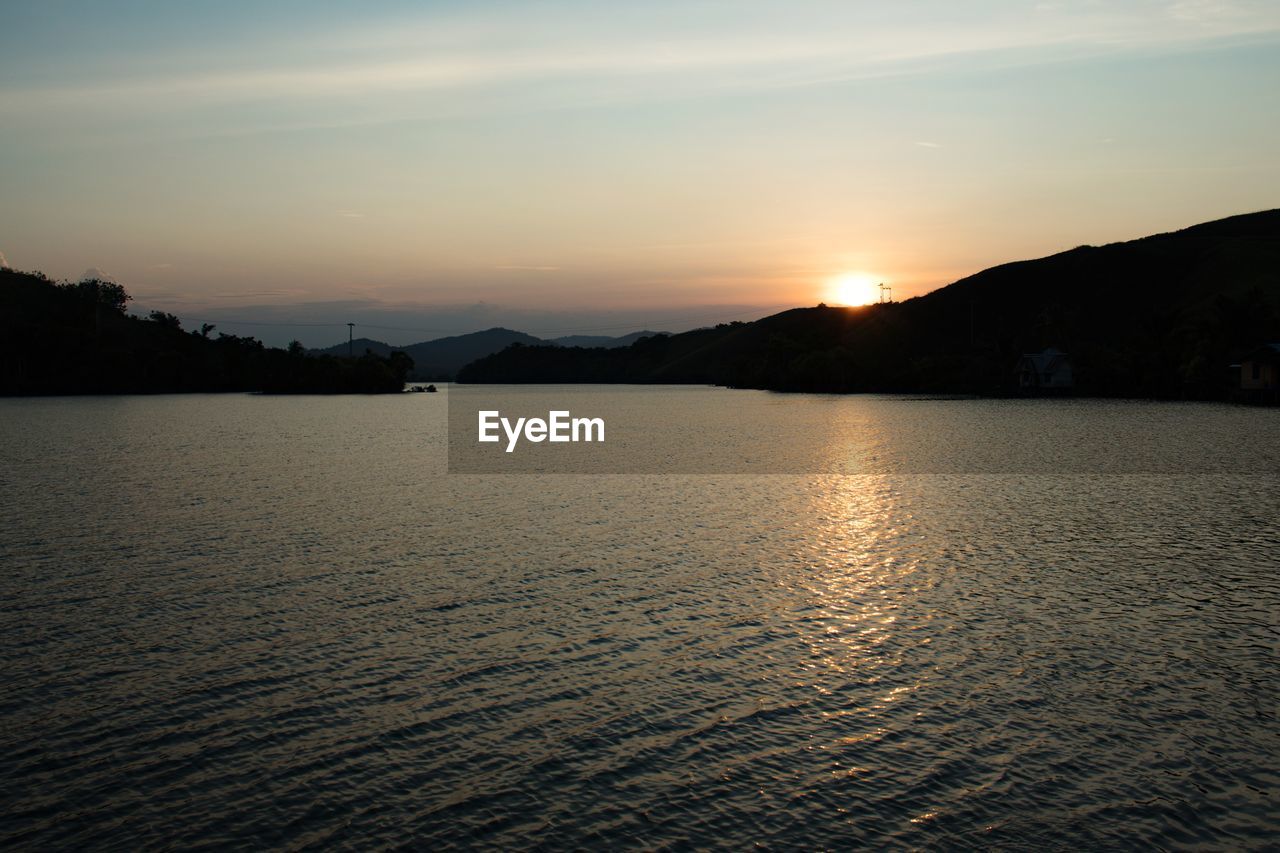 SCENIC VIEW OF SILHOUETTE MOUNTAINS BY SEA AGAINST SKY DURING SUNSET