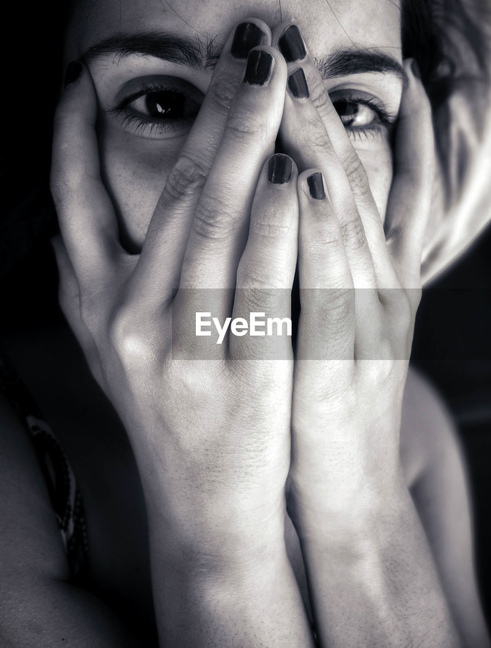 Close-up portrait of woman covering face with hands