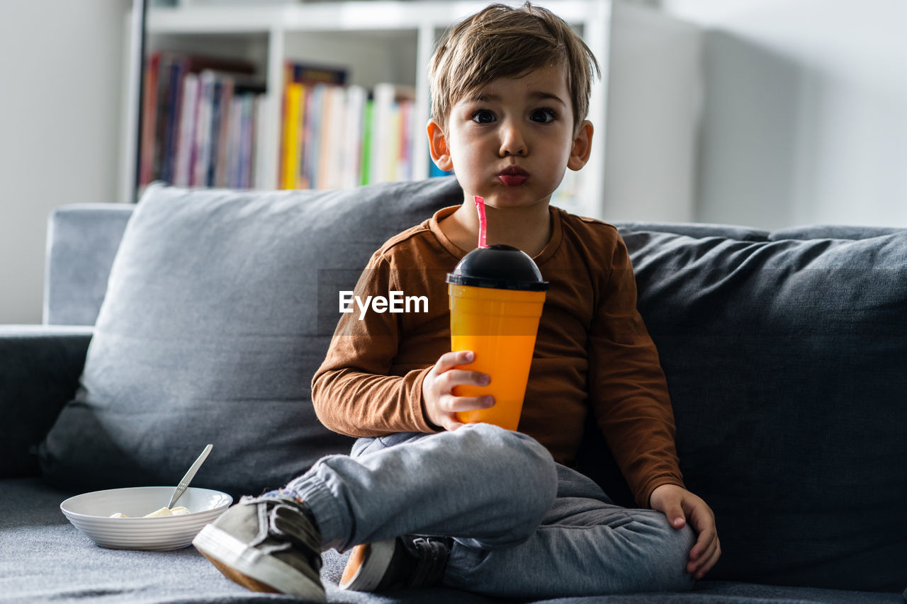 Portrait of boy sitting on sofa at home