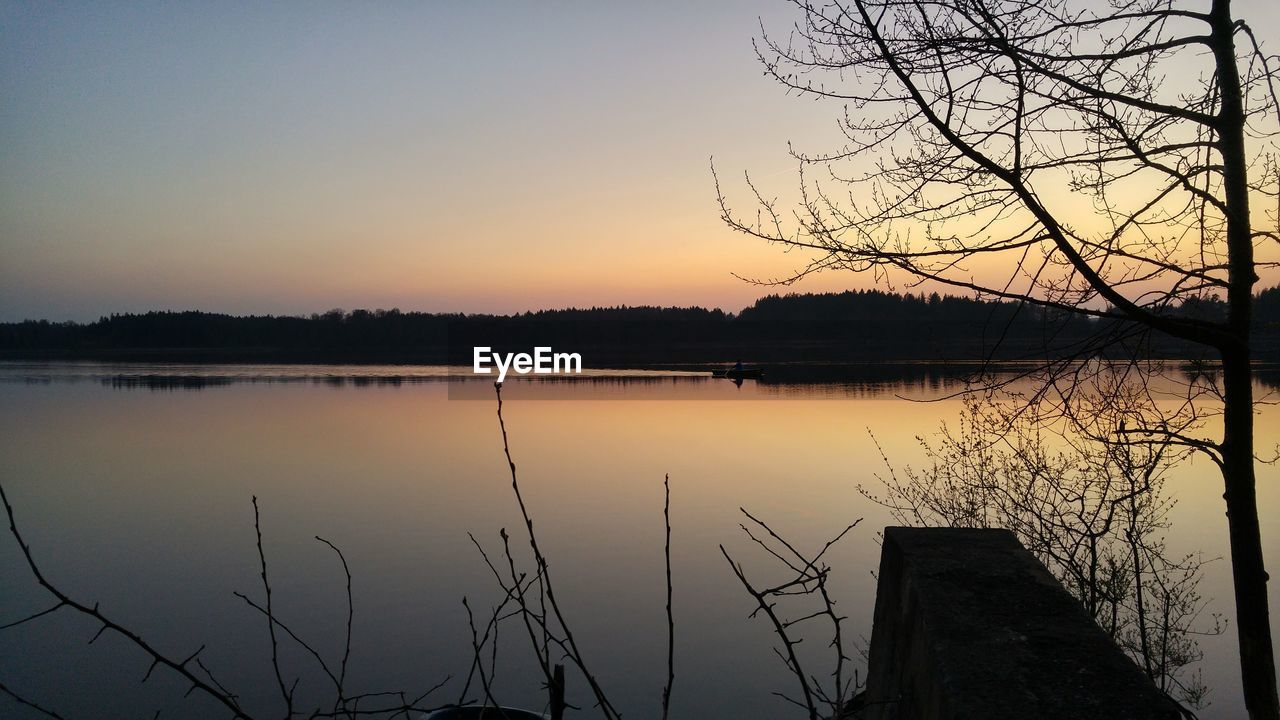 SILHOUETTE PLANTS BY LAKE AGAINST SKY DURING SUNSET