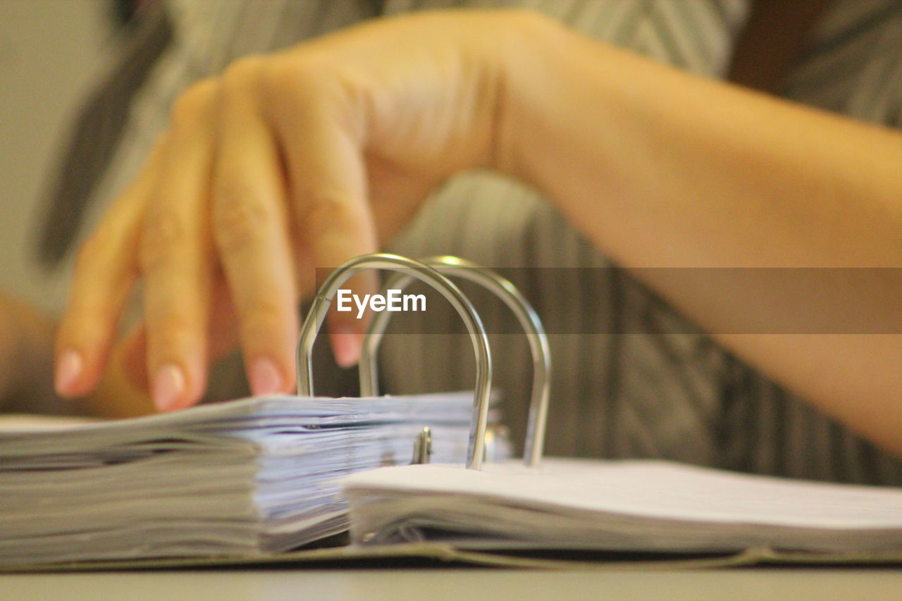 Close-up of person holding paper on table 