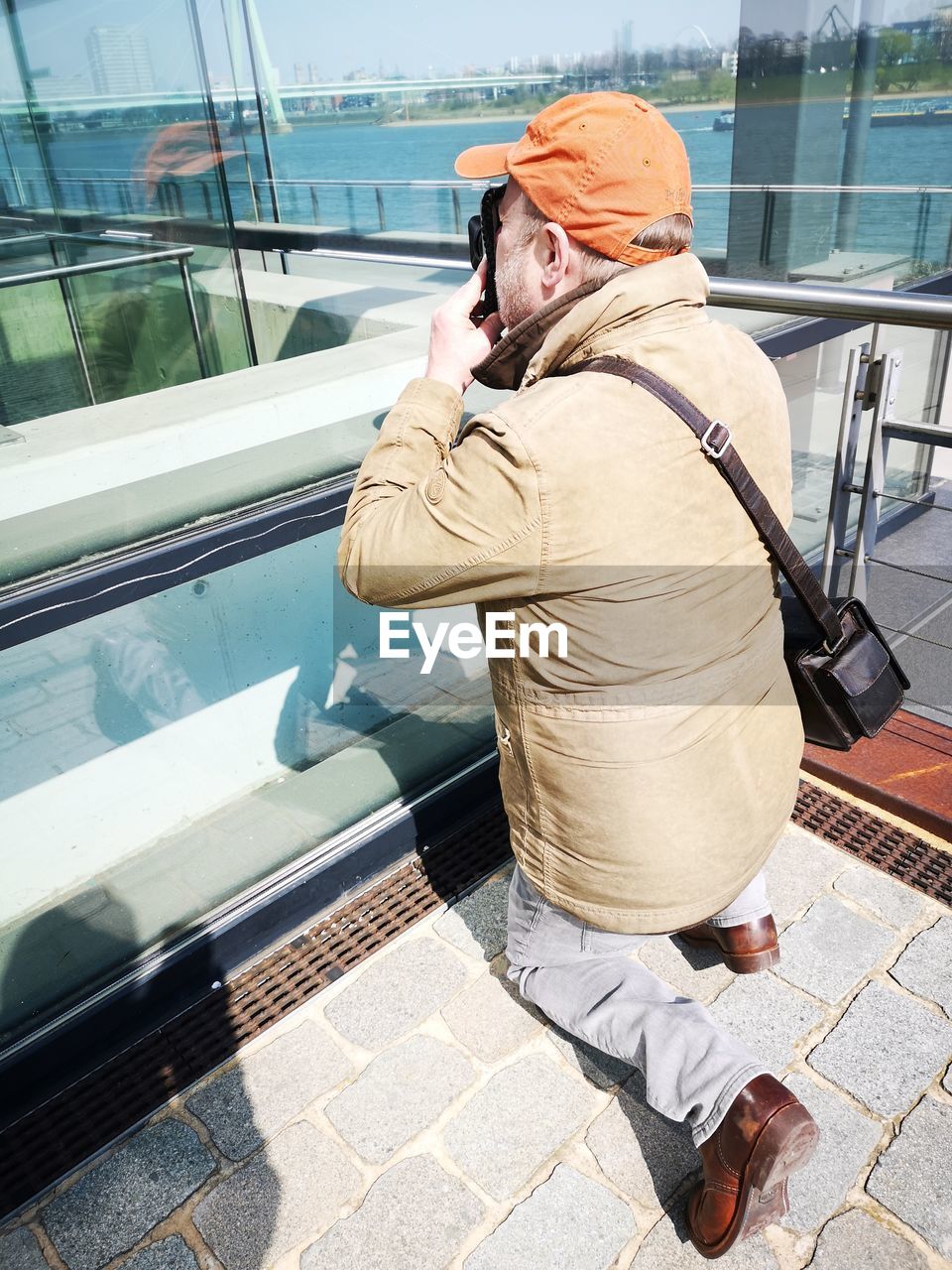 REAR VIEW OF MAN PHOTOGRAPHING THROUGH GLASS OF BUS