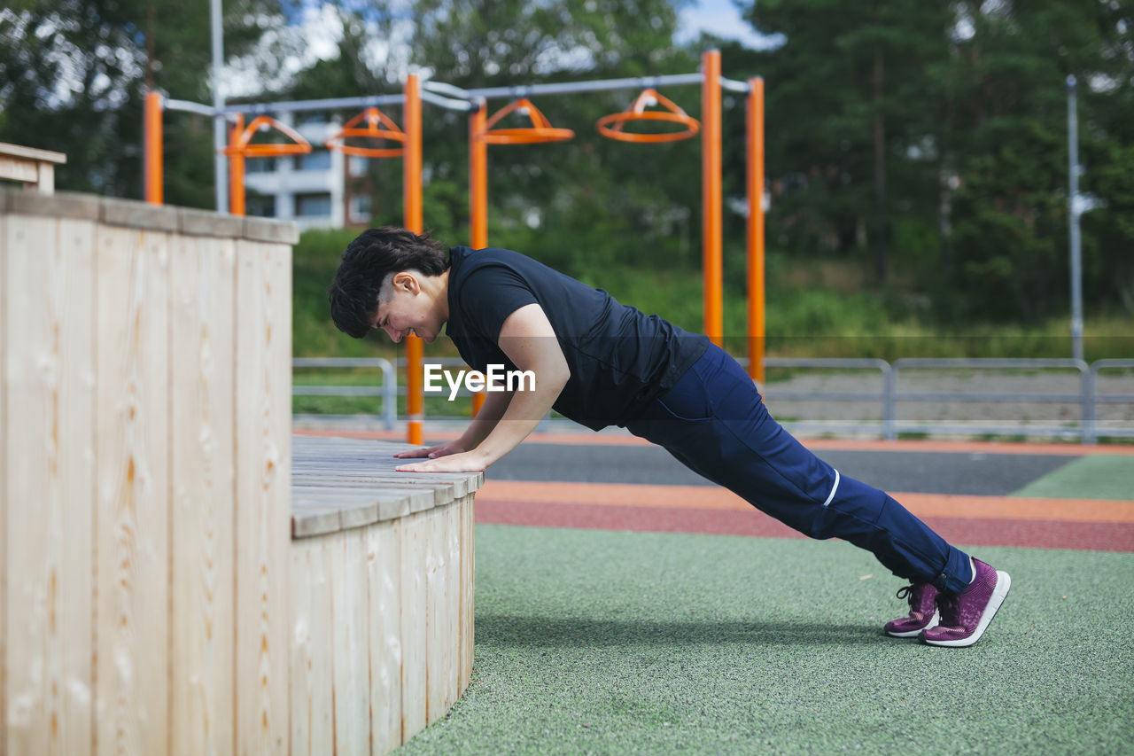 Young woman doing push-ups at outdoor gym