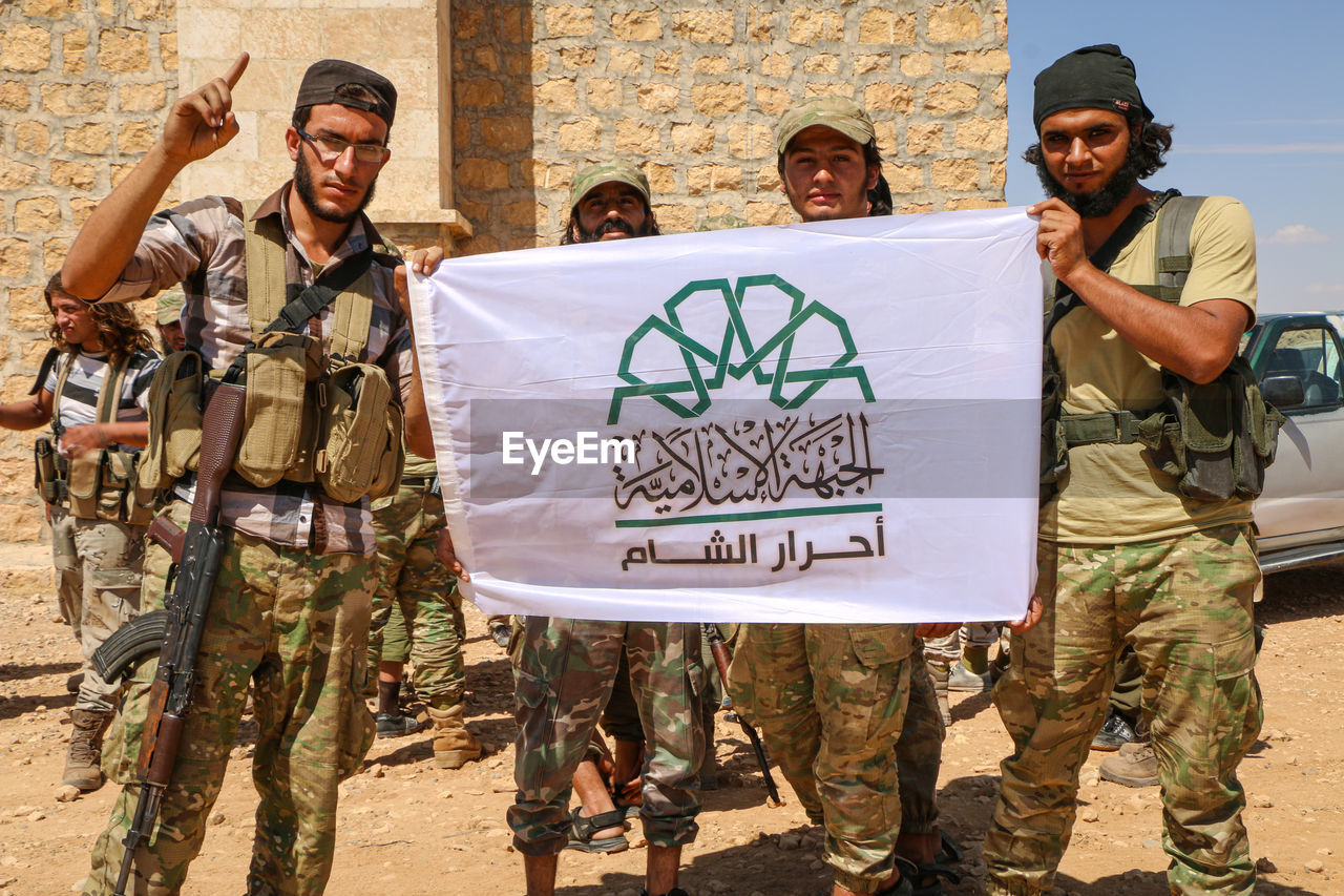 Portrait o soldiers holding banner standing outdoors
