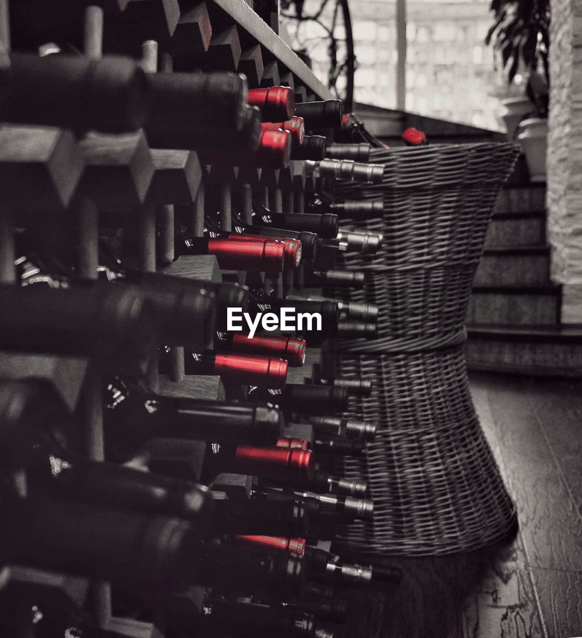 CLOSE-UP OF RED WINE BOTTLES IN SHELF