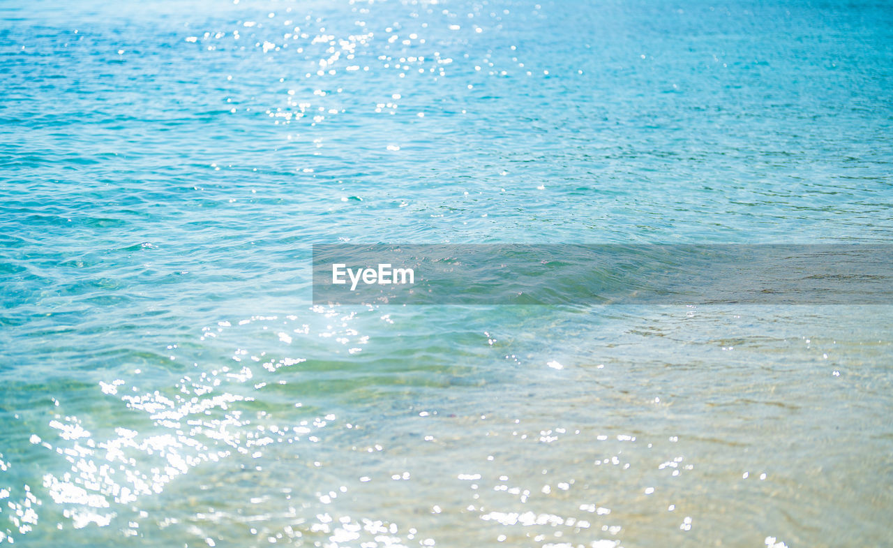 water, wave, sea, ocean, wind wave, beauty in nature, nature, blue, scenics - nature, azure, no people, tranquility, sunlight, shore, horizon, backgrounds, rippled, day, motion, tranquil scene, beach, full frame, outdoors, body of water, idyllic, land, coast, waterfront, high angle view