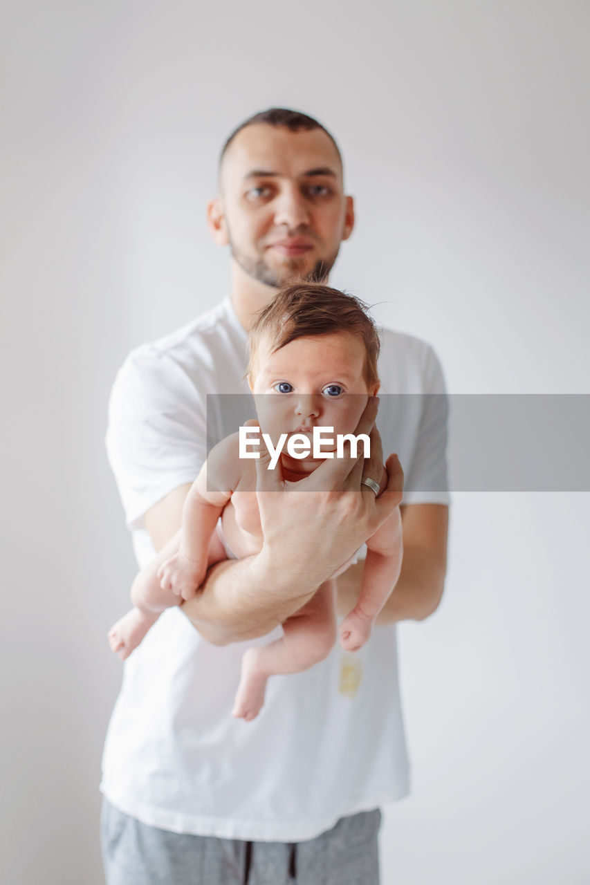 Portrait of man with cute daughter standing over white background