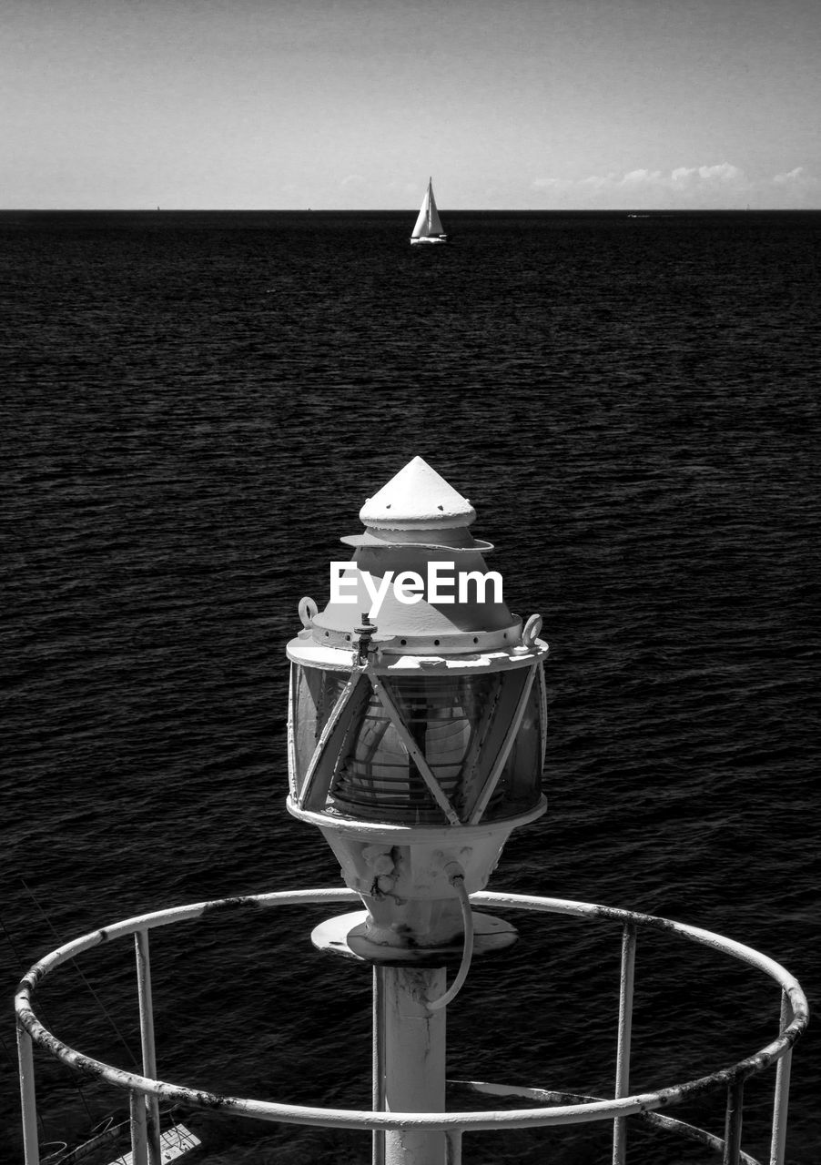 Sailboat sailing on sea against sky near lighthouse 