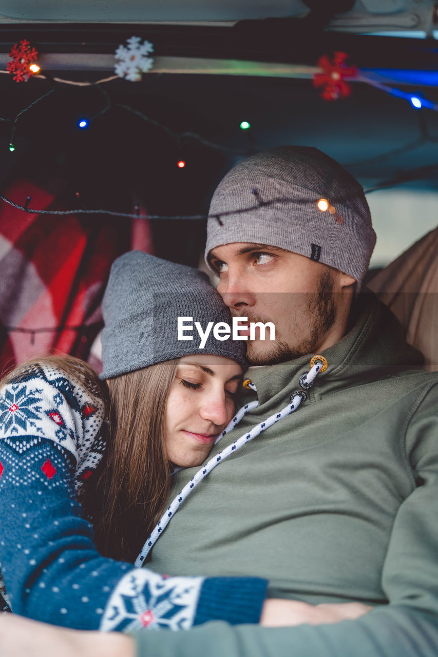 Couple embracing while sitting in car during winter