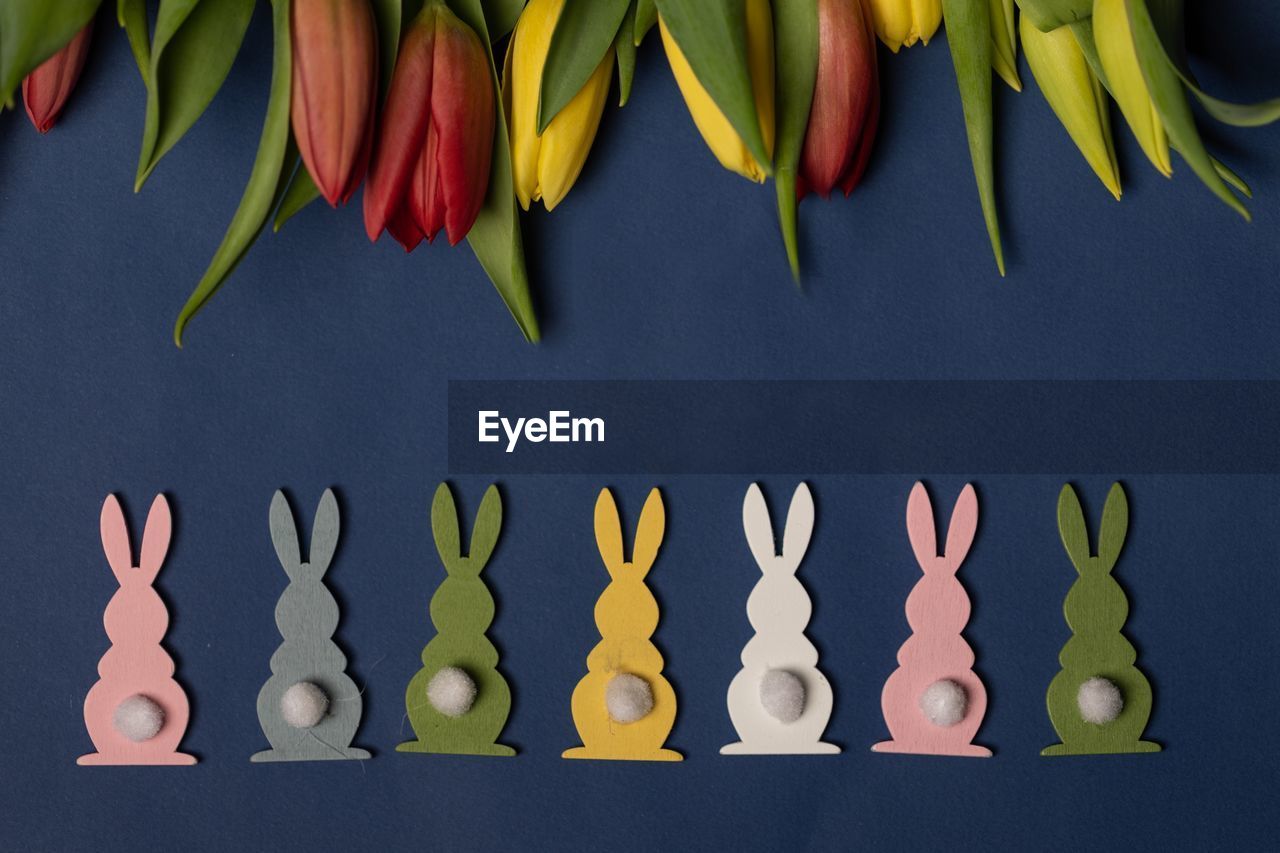 Directly above shot of multi colored easter bunnies by flowers on table