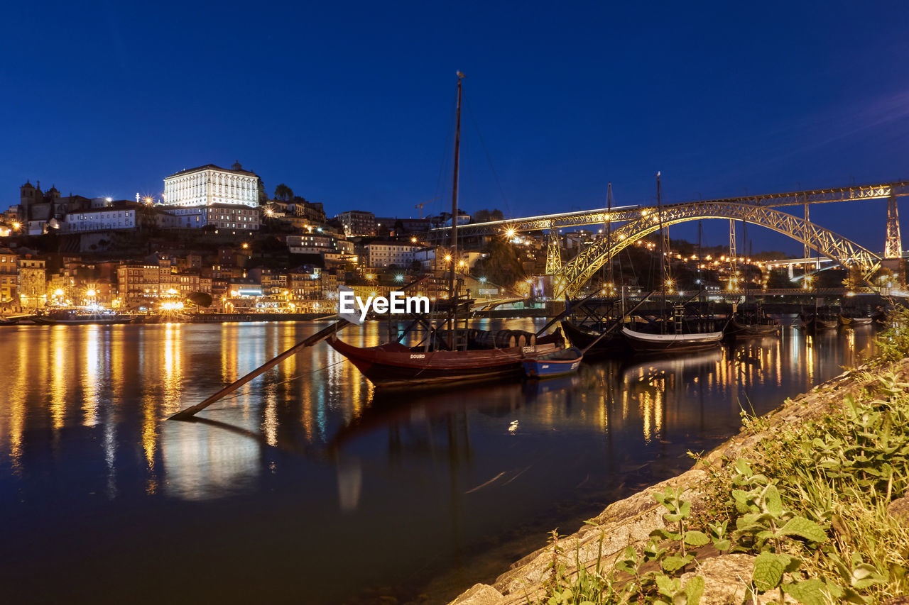 Illuminated bridge over river in city at night