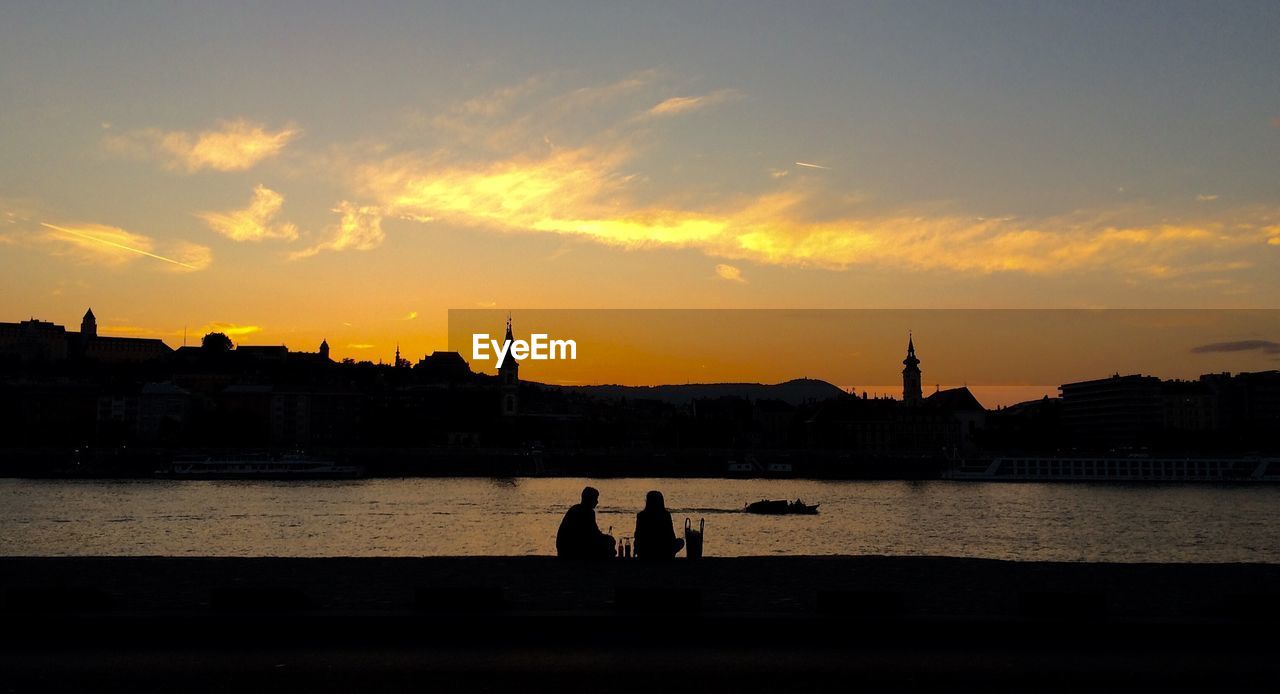 Silhouette couple overlooking calm river