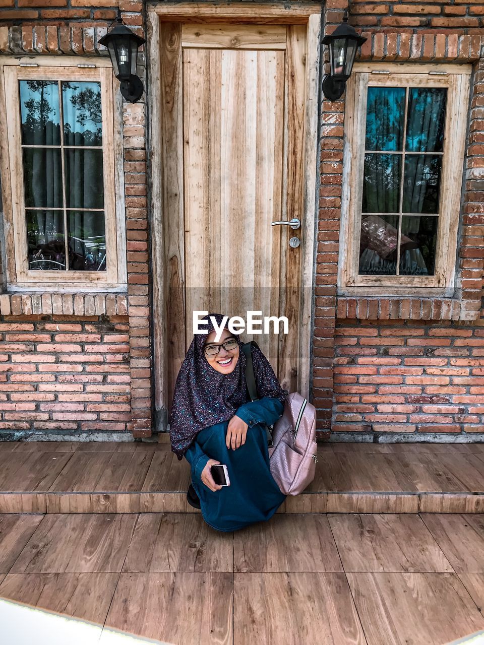 PORTRAIT OF GIRL SITTING ON WOODEN DOOR