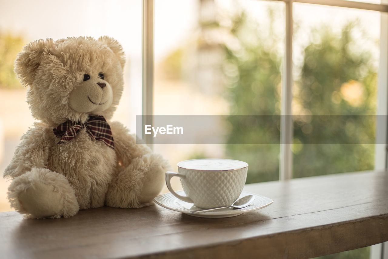 Close-up of teddy bear and coffee cup on table