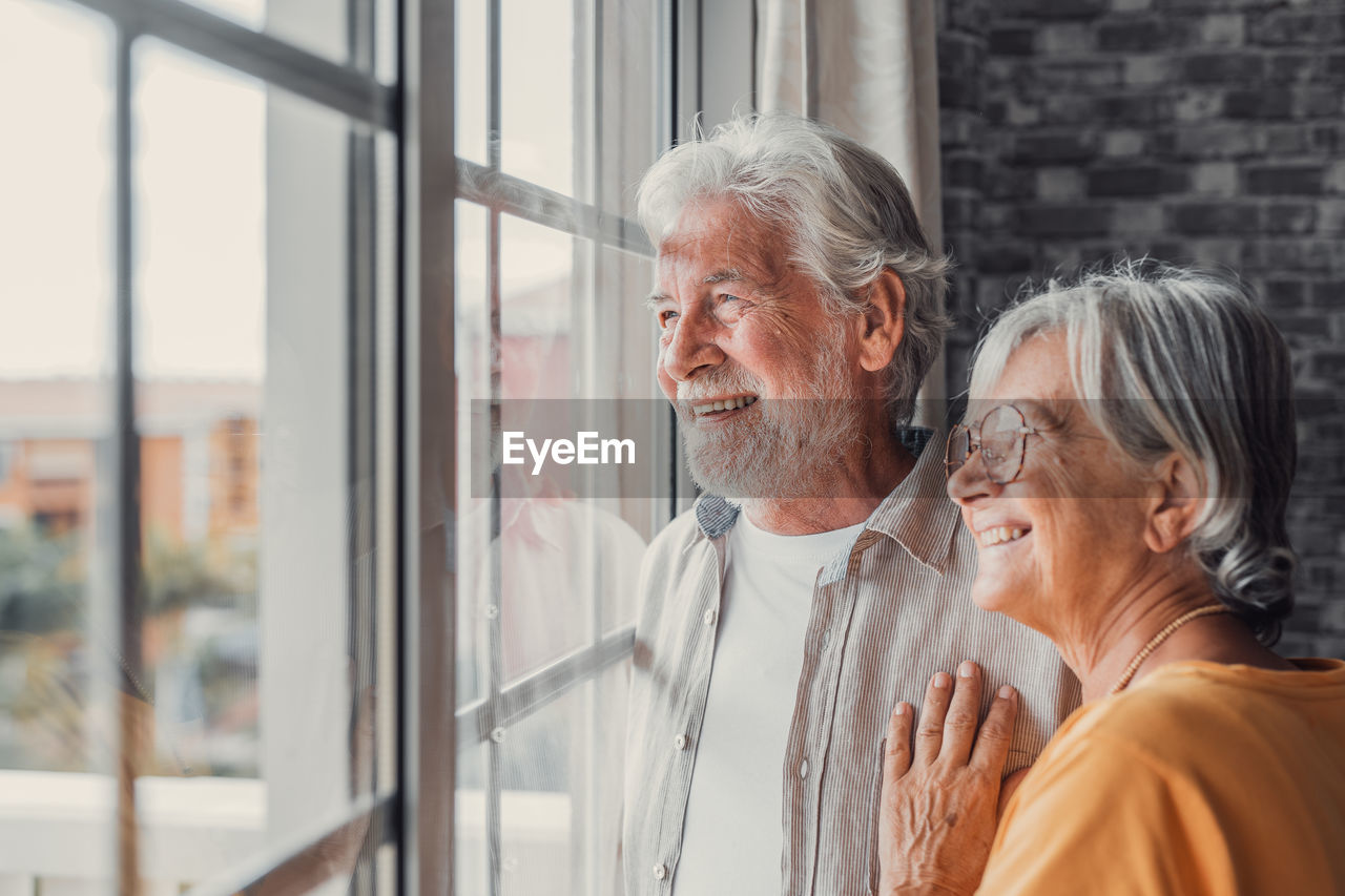 side view of senior couple looking through window