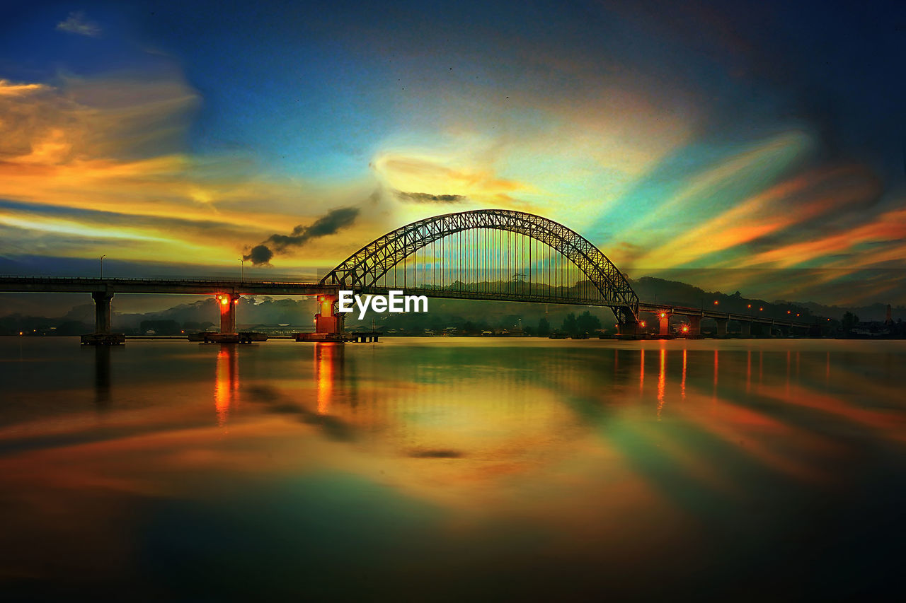 Arch bridge over river against sky during sunset