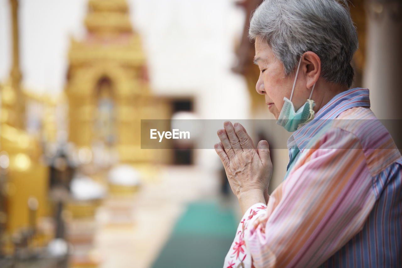 Woman with hands joined at temple