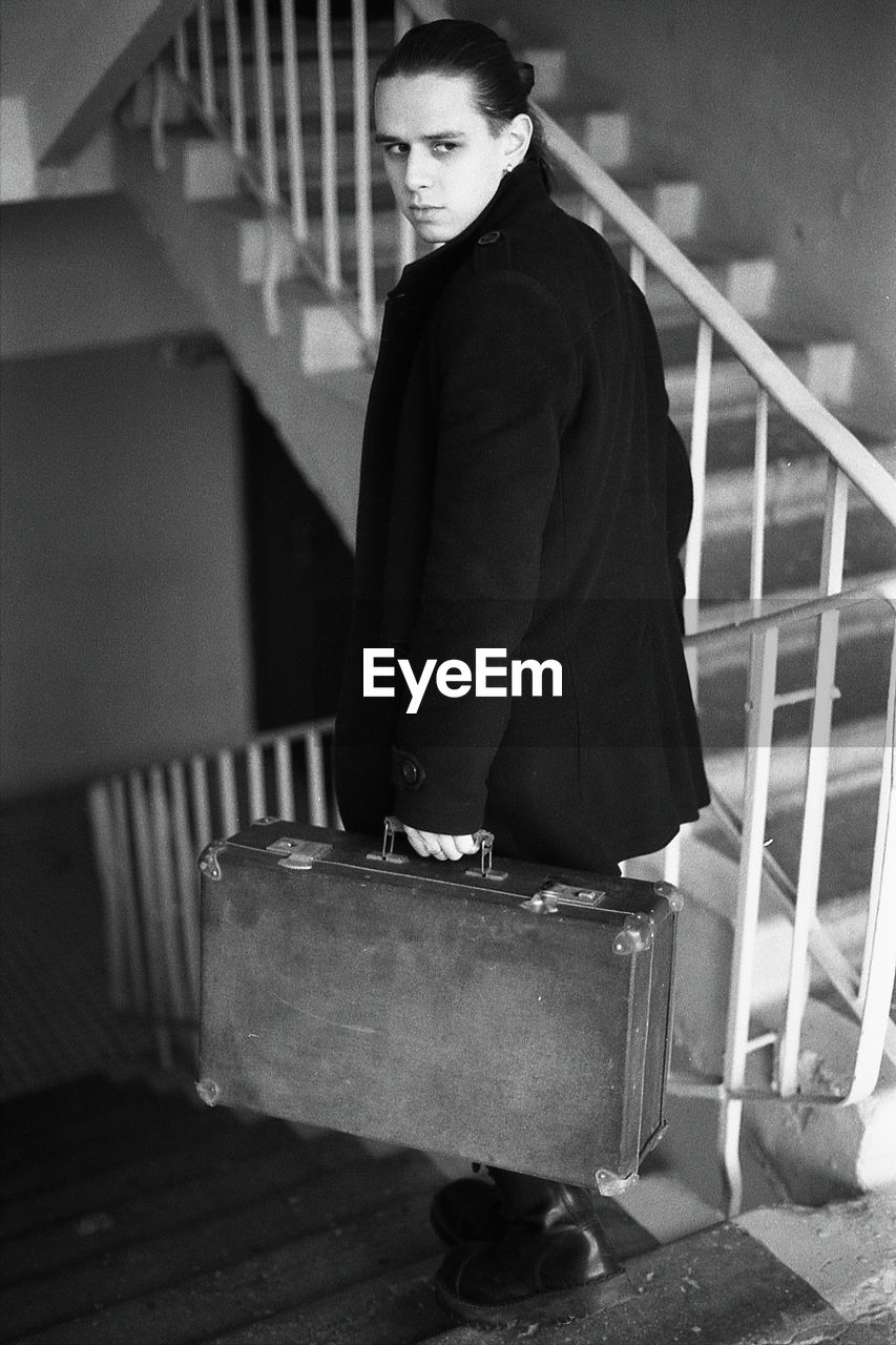 Young man holding briefcase on steps