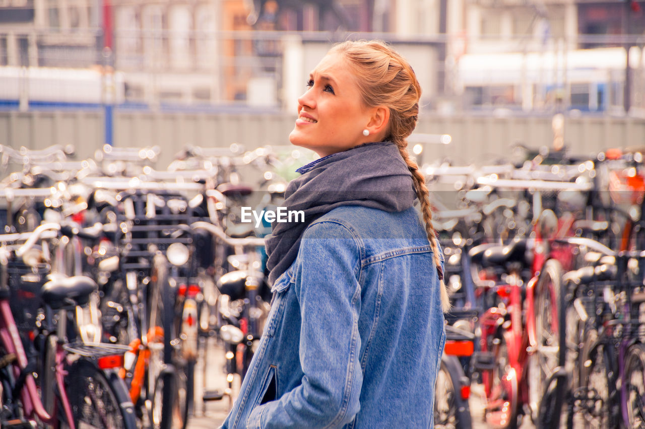 Smiling young woman standing against bicycles