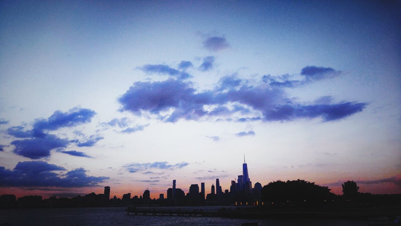 SILHOUETTE OF CITY SKYLINE AGAINST CLOUDY SKY