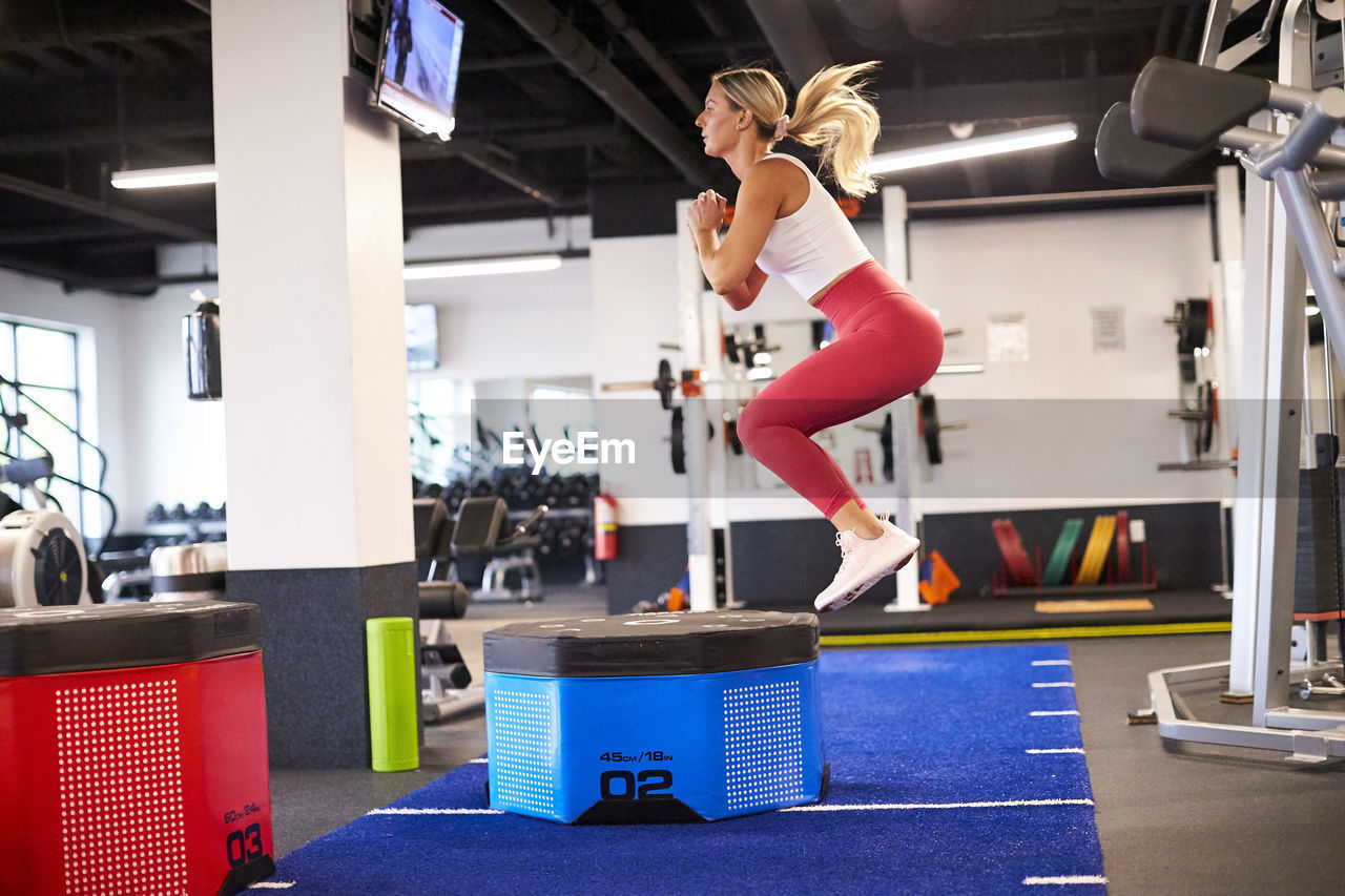 A woman box jumping in the gym.
