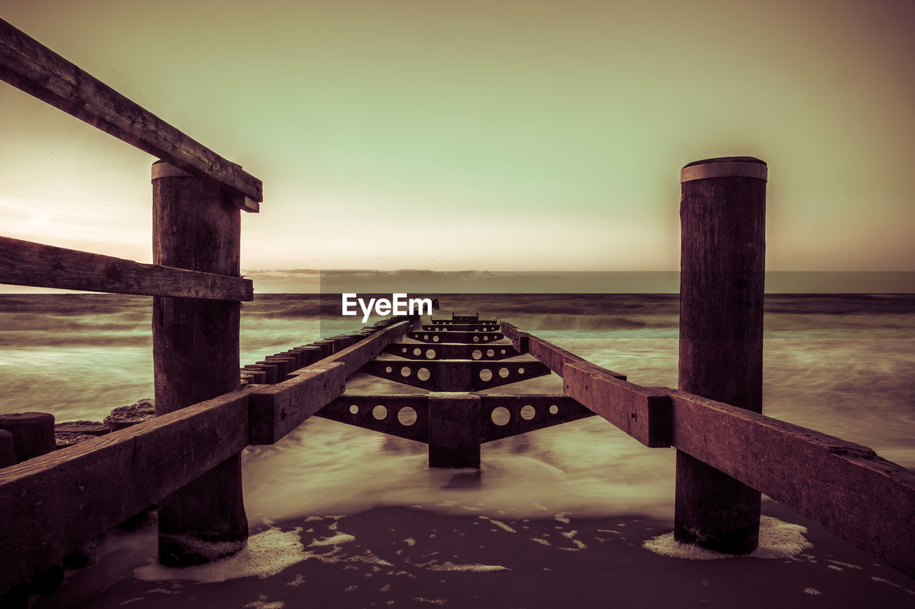 Wooden pier on sea against sky