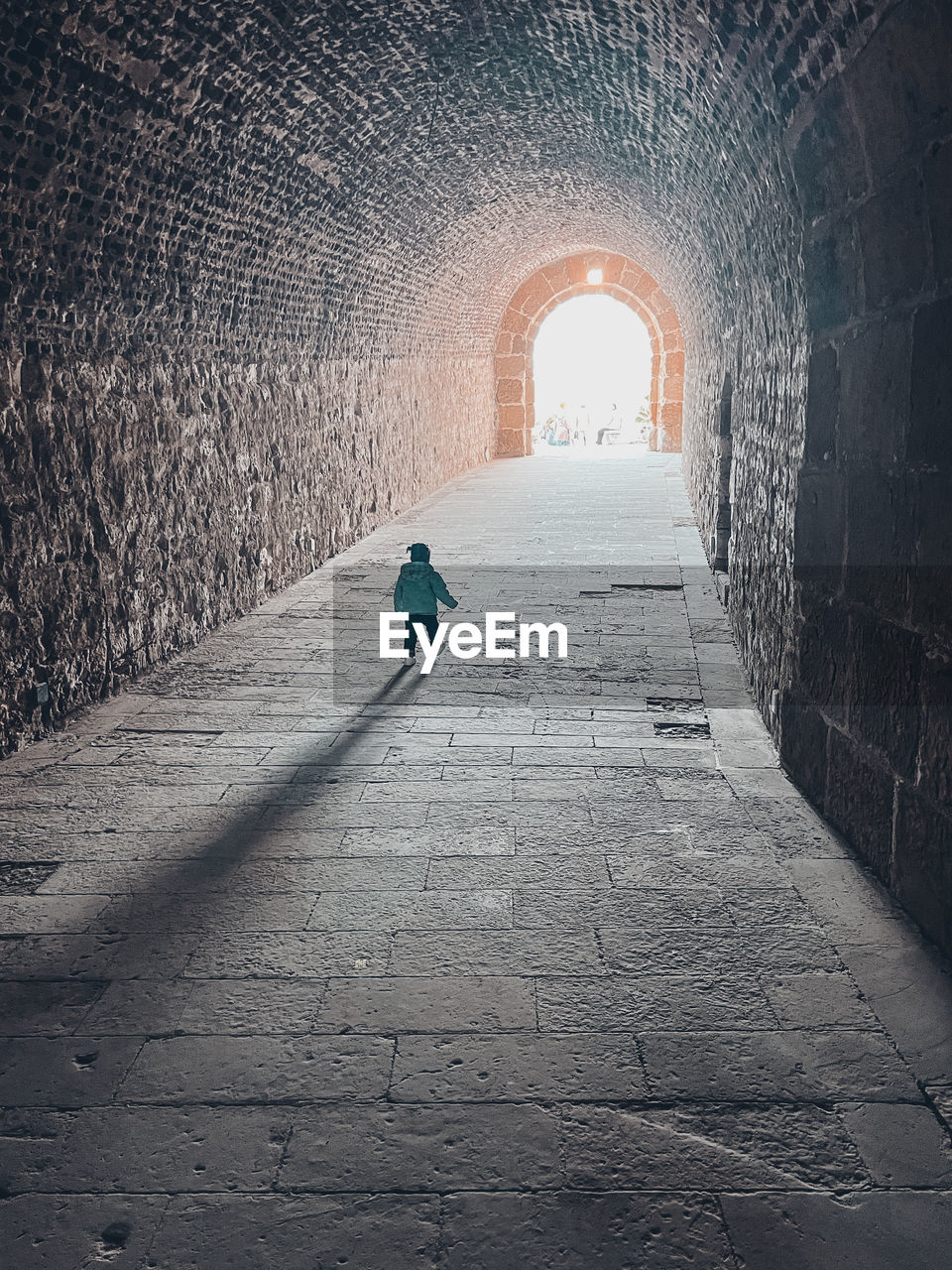 Rear view of child walking in tunnel