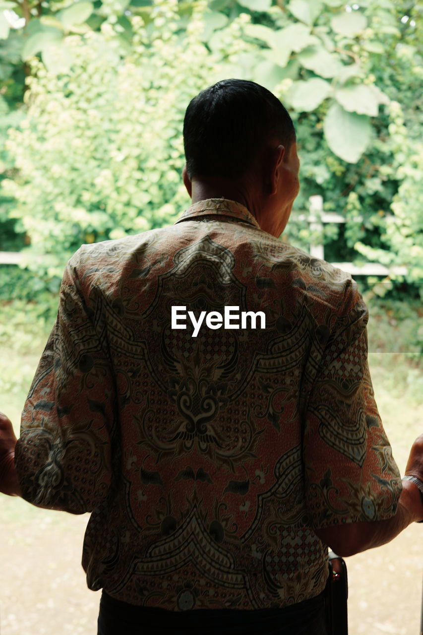 Rear view of man standing against plants