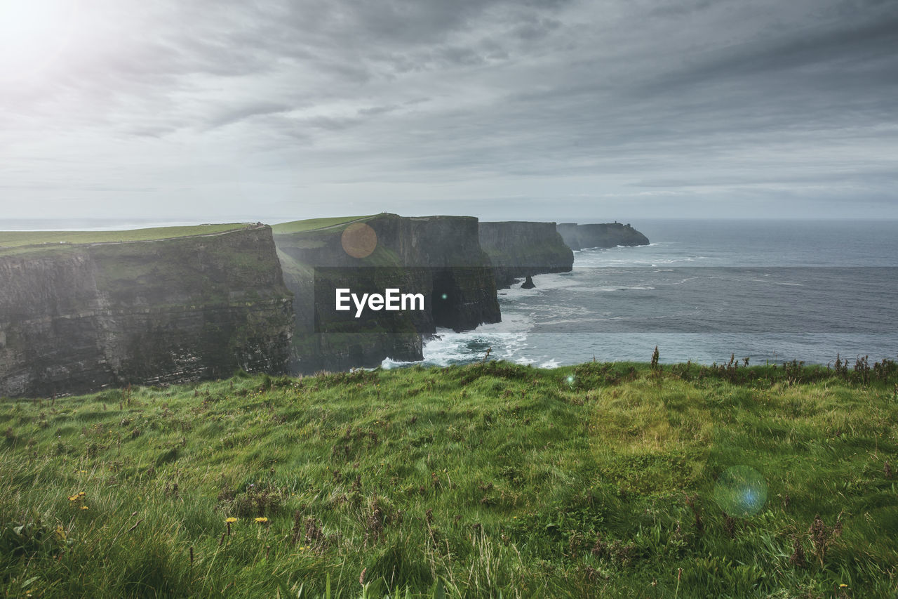 SCENIC VIEW OF SEA AND CLIFF AGAINST SKY