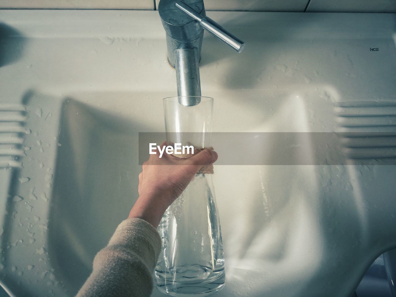 Cropped hand feeling bottle in sink