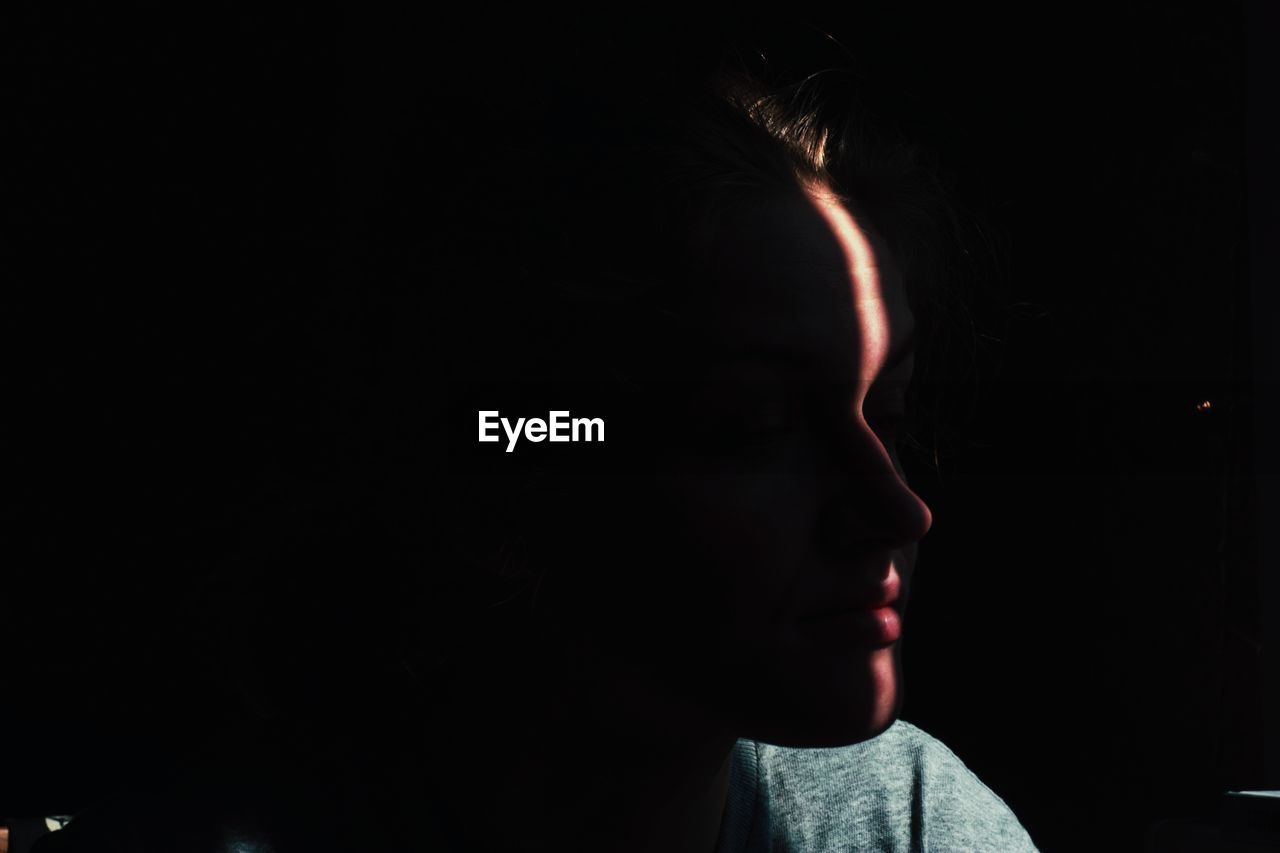 Close-up of woman against black background