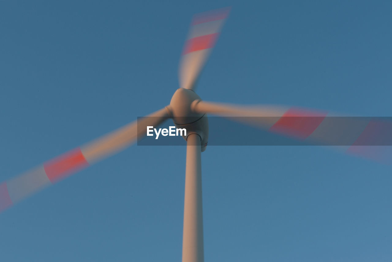 Low angle view of wind turbine against blue sky