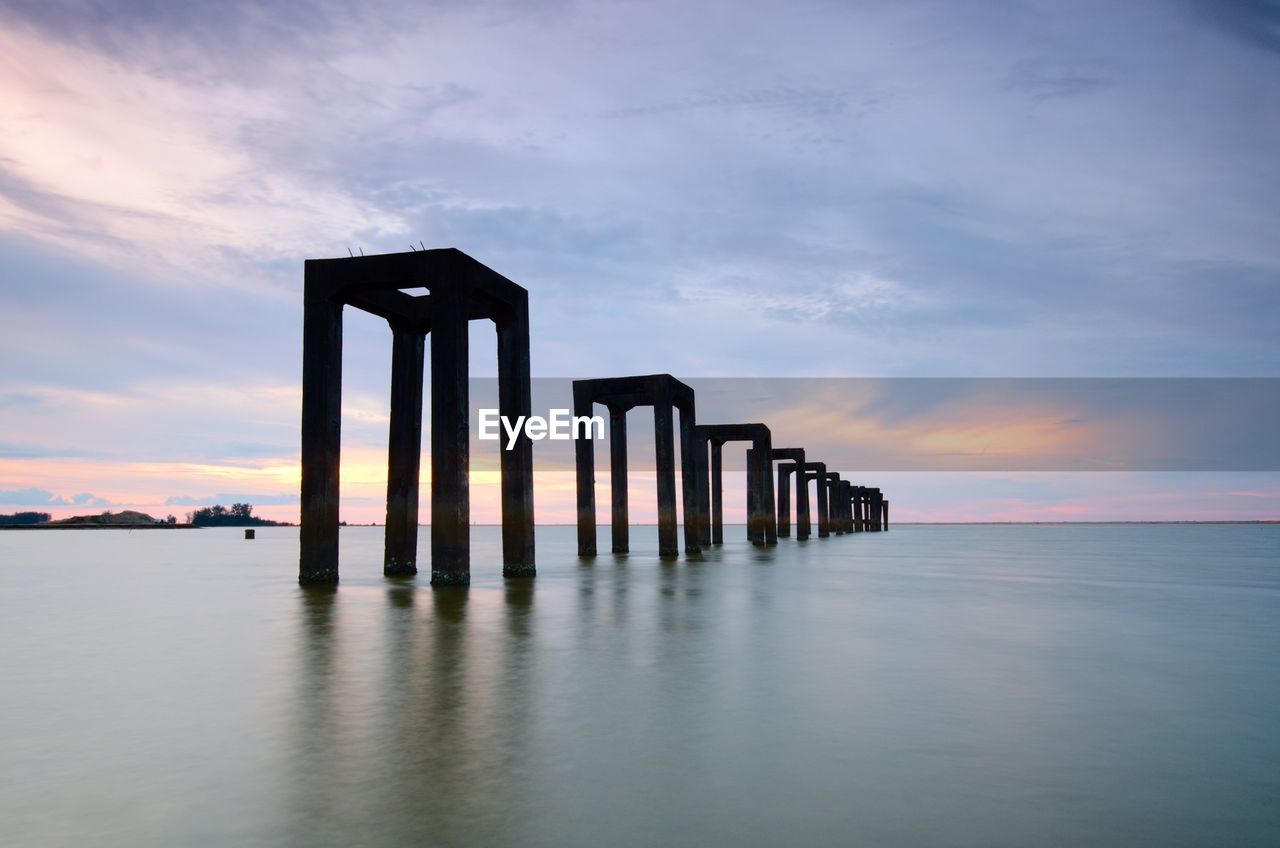 Pier over sea against sky during sunset