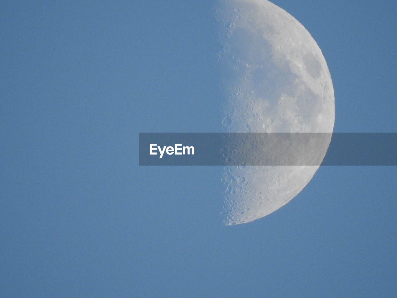 LOW ANGLE VIEW OF HALF MOON AGAINST BLUE SKY