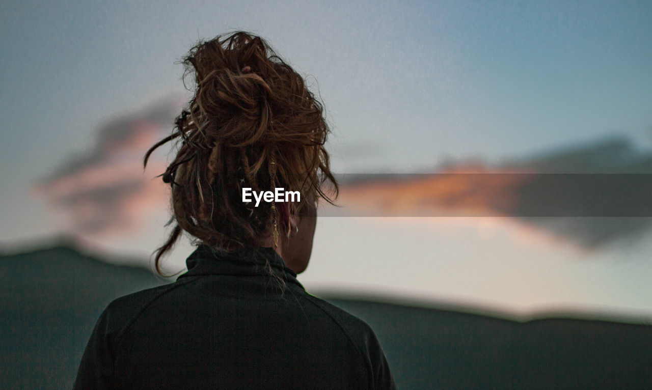 Rear view of woman looking at view during sunset