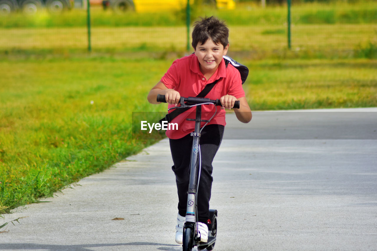 Portrait of smiling boy riding push scooter