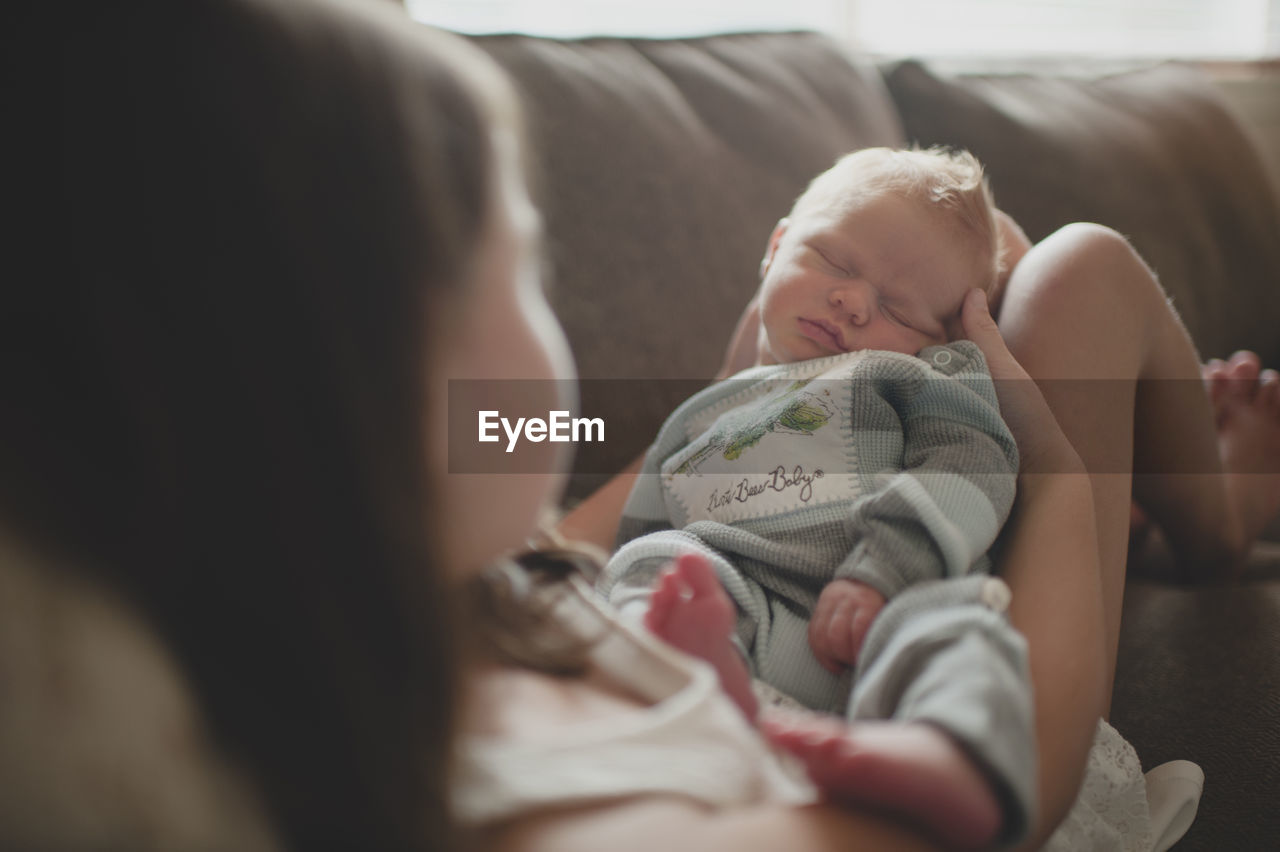 Close-up of girl playing with baby boy while sitting on sofa at home