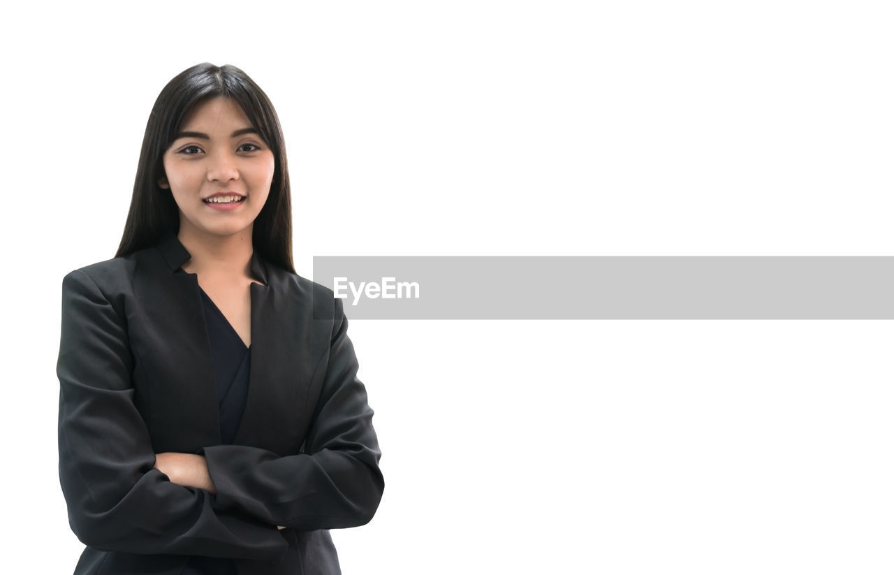 Portrait of businesswoman with arms crossed standing against white background