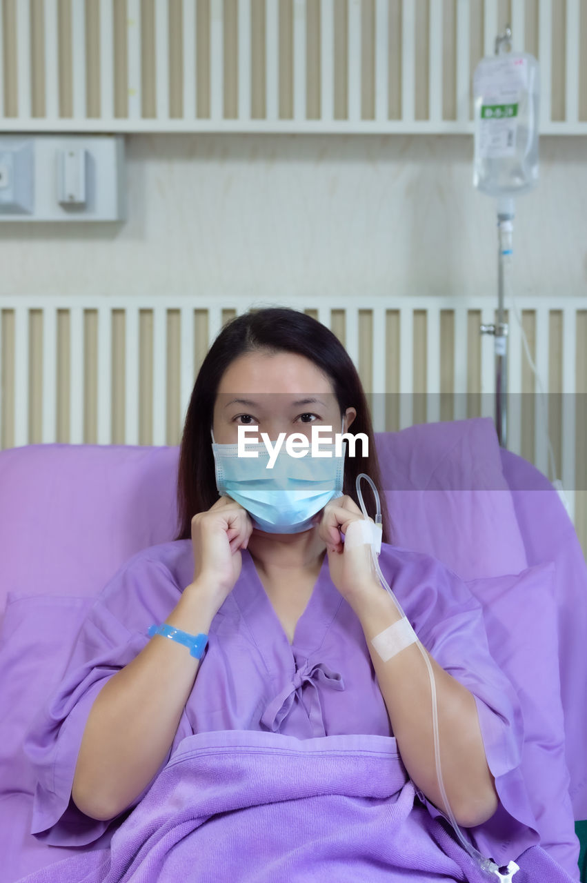 Female patient is smiling and showing medical mask in hospital room. medical healthcare concept.