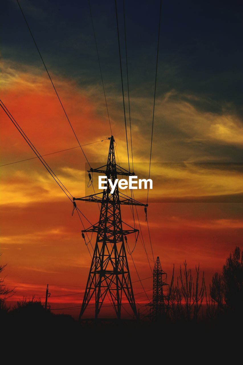 Low angle view of electricity pylon against cloudy sky