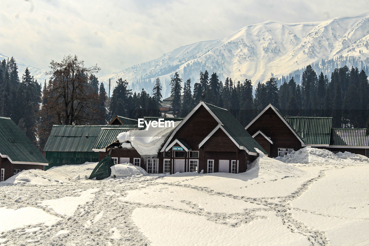 HOUSES ON SNOW COVERED FIELD AGAINST SKY