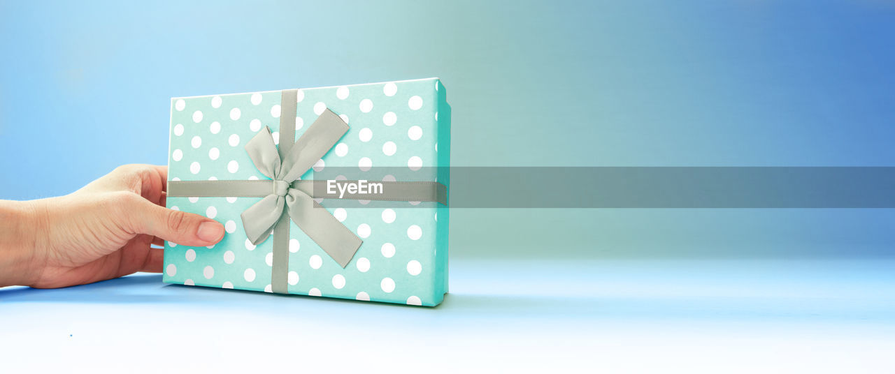 Green giftbox with hand on deep green background for your celebration. copy space.