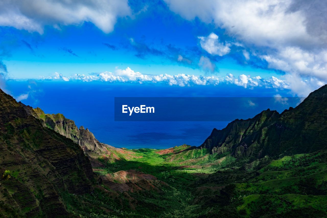 Scenic view of mountains by sea against cloudy sky