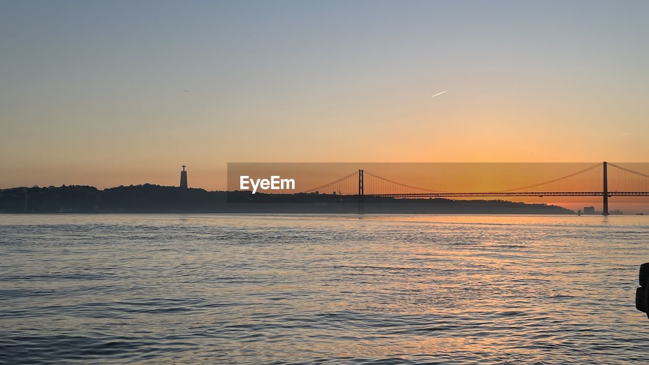 sky, water, bridge, architecture, transportation, built structure, suspension bridge, sea, travel destinations, sunset, horizon, nature, travel, city, dusk, beauty in nature, scenics - nature, tourism, evening, bay, engineering, bay of water, dramatic sky, tranquility, copy space, landscape, tranquil scene, urban skyline, cityscape, mode of transportation, reflection, atmospheric mood, sunlight, building exterior, environment, outdoors, idyllic, twilight, sun, ocean, nautical vessel, shore, land, moody sky, wave, holiday, vehicle, silhouette, motion, trip, beach, vacation, city life, cloud, fog, rippled, business finance and industry, coast, horizon over water, building, coastline, summer, water's edge, illuminated, awe, low tide, seascape, tide, waterfront, panoramic, blue