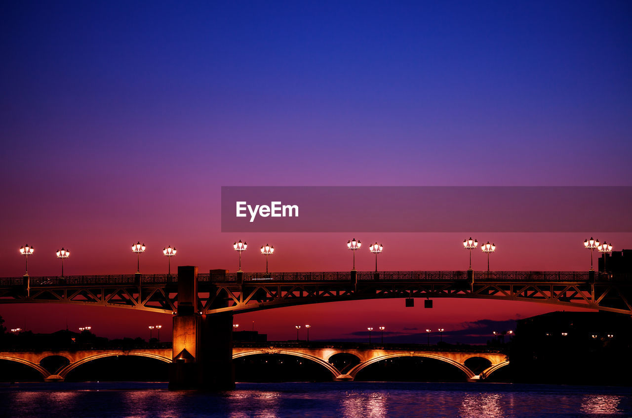 Bridge over river against sky at dusk