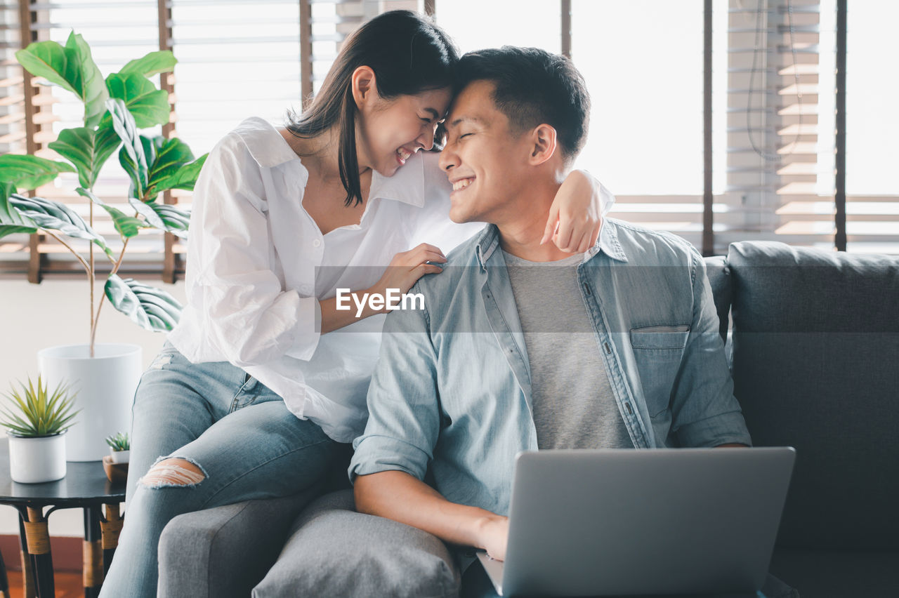 Smiling couple with face to face sitting on sofa at home