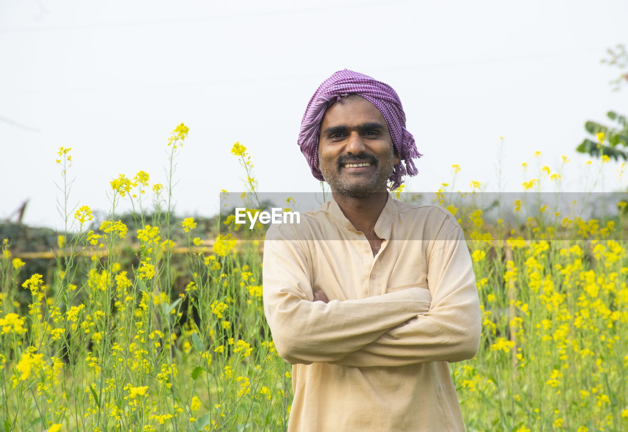 Happy indian farmer standing in agricultural field