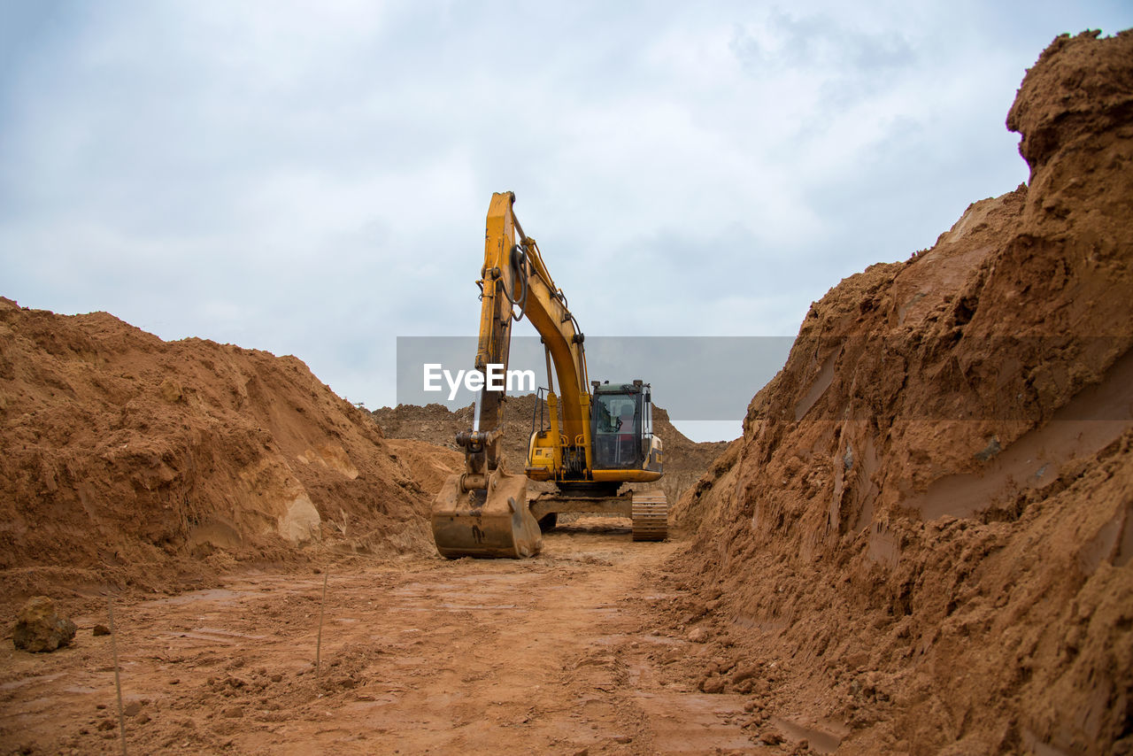 Excavator digs a large trench for pipe laying. backhoe during earthmoving at construction site. 